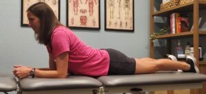 A patient presses up on her elbows to perform lumbar extension exercise for low back pain