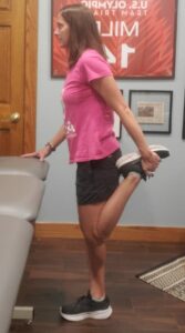 A physical therapy patient performs a quad stretch