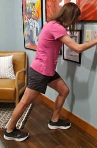 A physical therapy patient performs a stretch for her calf